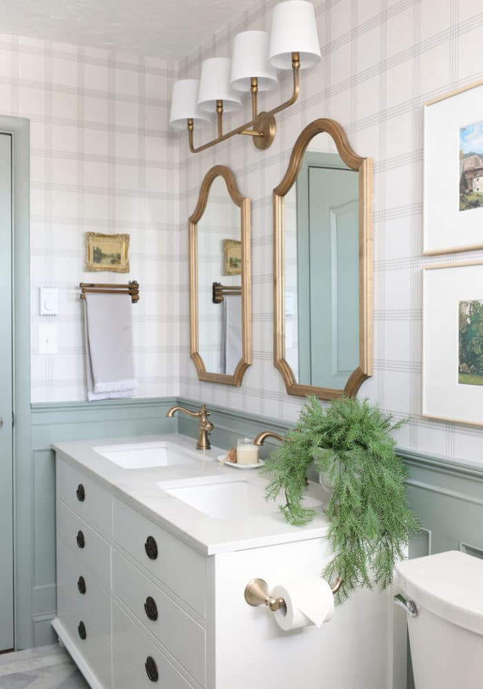 modern bathroom with white vanity and half wall painted Sherwin Williams Acacia Haze and plaid wallpaper on the walls.