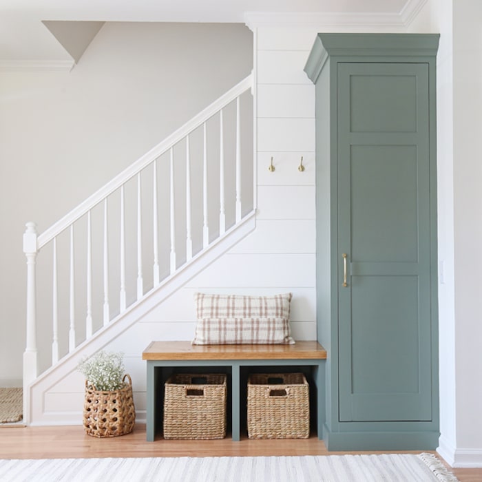 entryway with shiplap white walls, stairwell rails and built-in cabinet and bench painted Sherwin Williams Retreat.