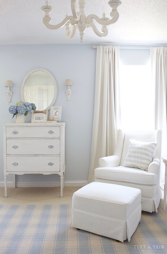 Traditional boy's nursery with blue walls and white glider and ottoman. 