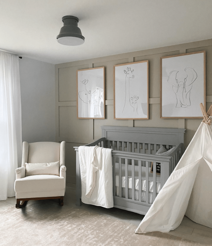 Animal art hanging over a gray crib in a nursery with Revere Pewter walls and a white glider. 