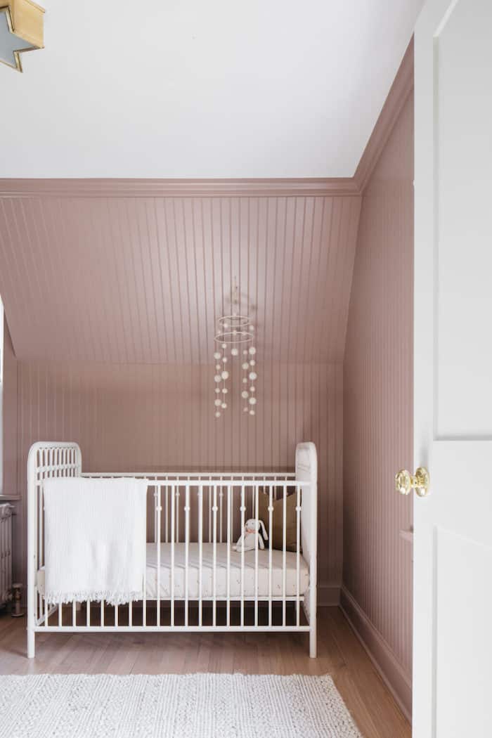 Seaside Sand (pink) walls with beaboard and a white crib with a mobile hanging over it.