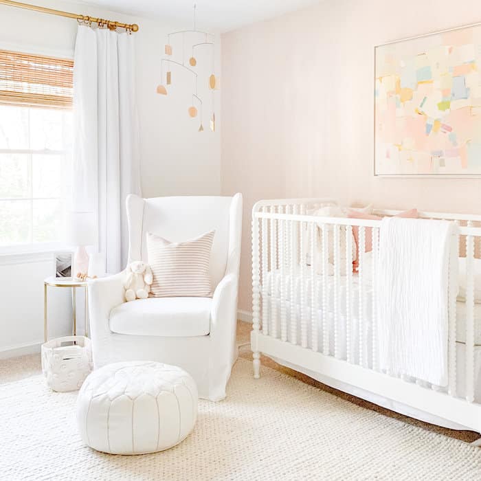 Girl's nursery with an accent wall of Schumacher Raindots Polka Dots wallpaper in Washed Pink.