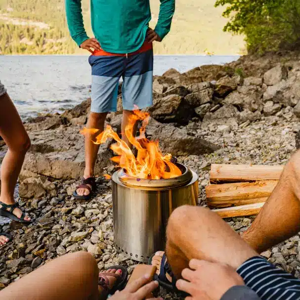 a Solo stove fire pit on a beach with people around it.