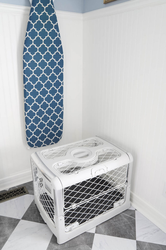 Revol Diggs dog crate in white with a gray pad cover in a laundry room.