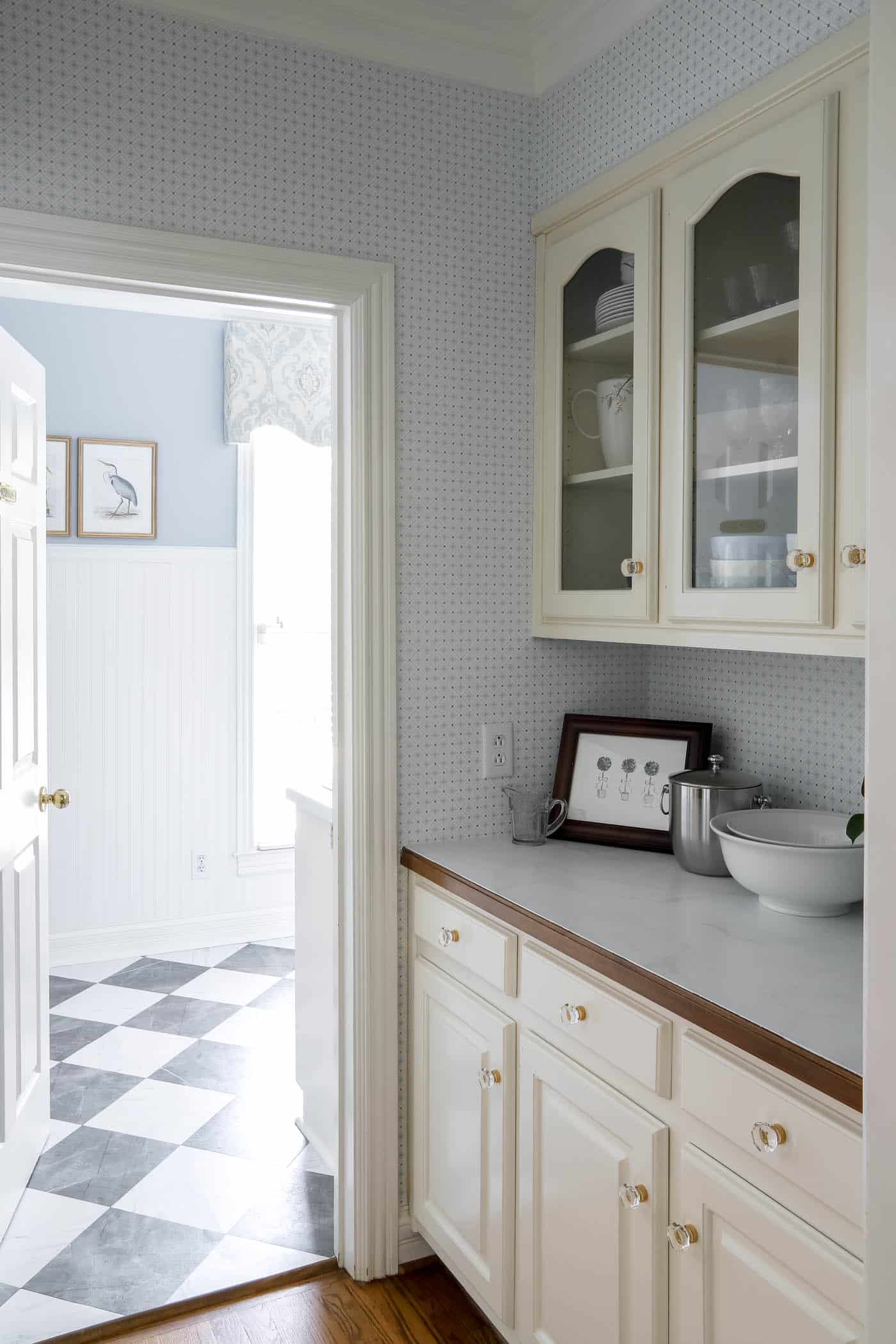 butler's pantry with blue and white wallpaper walking into a blue and white laundry room.