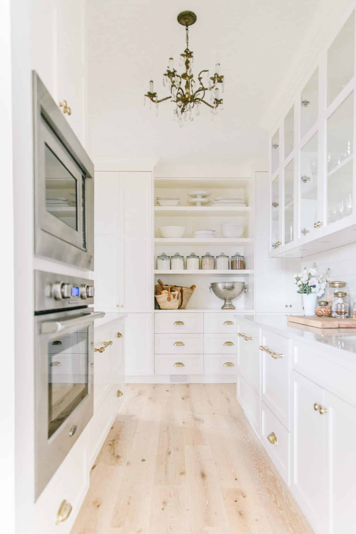 A white scullery combines a perfect balance of open shelving, minimal exposed food storage and two spacious counters for tasks.