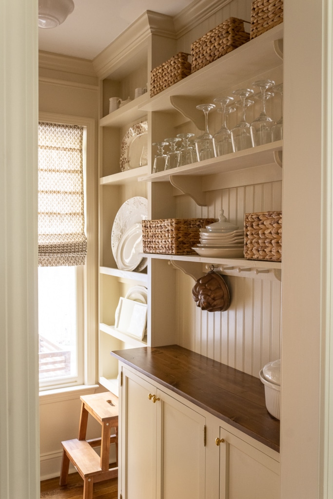 creamy warm white butler's pantry with wood countertops and open shelves with a peg rail.