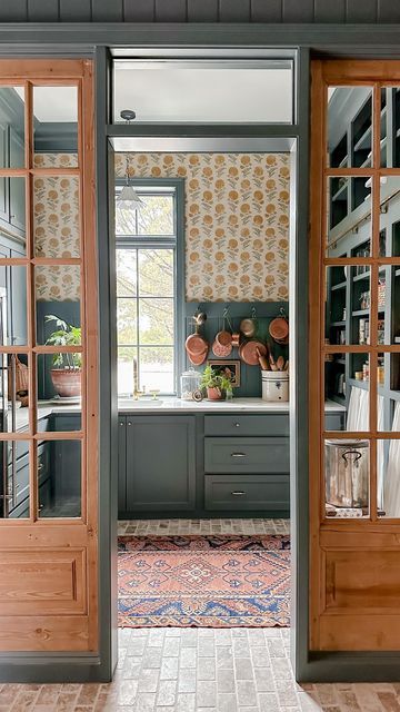 Funky scullery with brick flooring, green painted cabinets and bold yellow floral wallpaper.