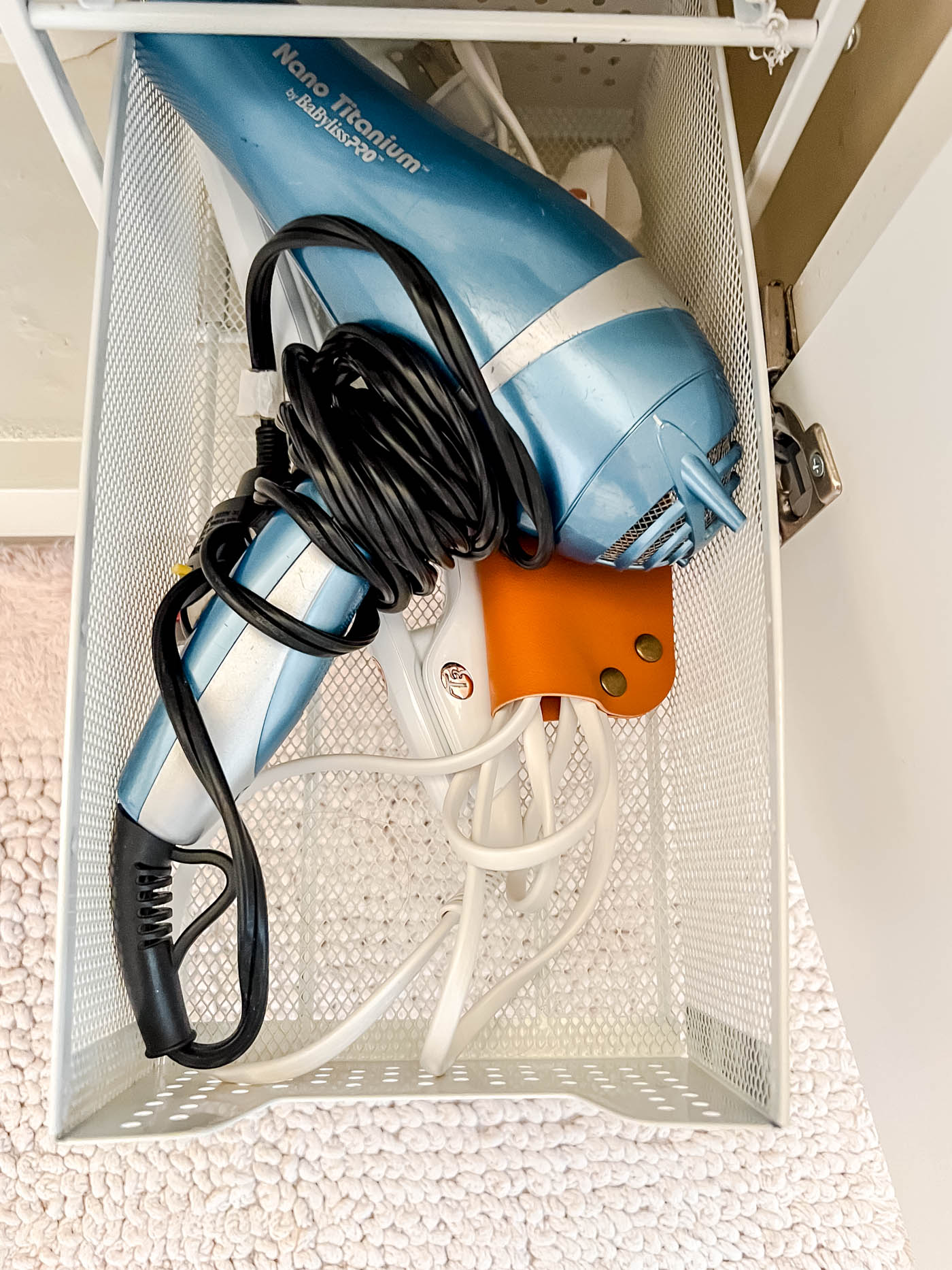 Dryer and straightening irons in the under-the-sink storage.