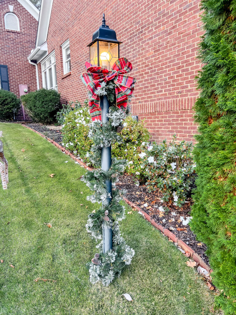 lamppost with holiday garland and red plaid bow.
