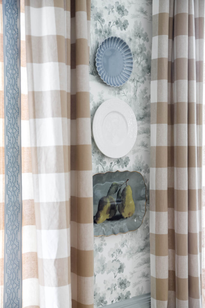 blue, green and white plates on a wall with toile wallpaper.