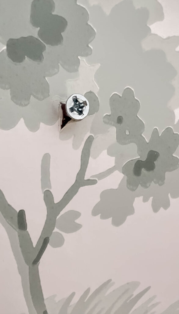 cut a piece of wallpaper before screwing or nailing holes in the wall. 