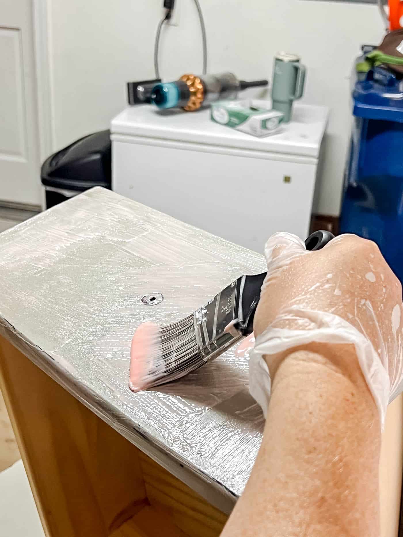 applying chemical stripped to a drawer front to strip the paint.