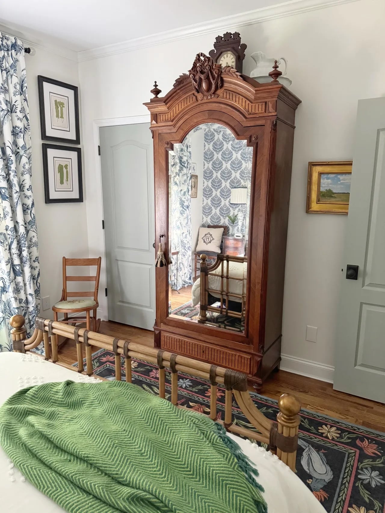 chinoiserie style brown armoire in a bedroom with light colored walls.