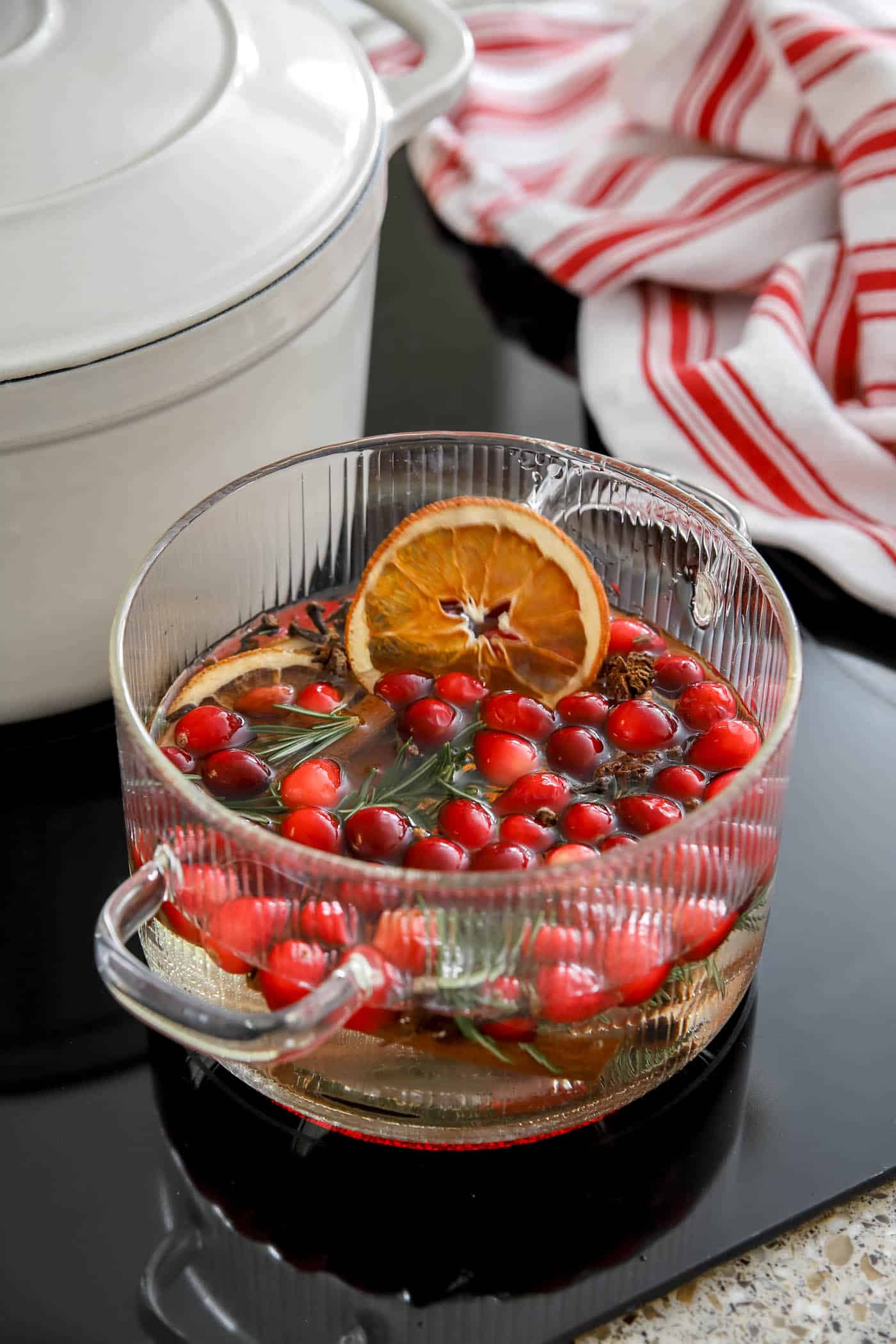 clear pot with Christmas simmering ingredients inside it on the stovetop.