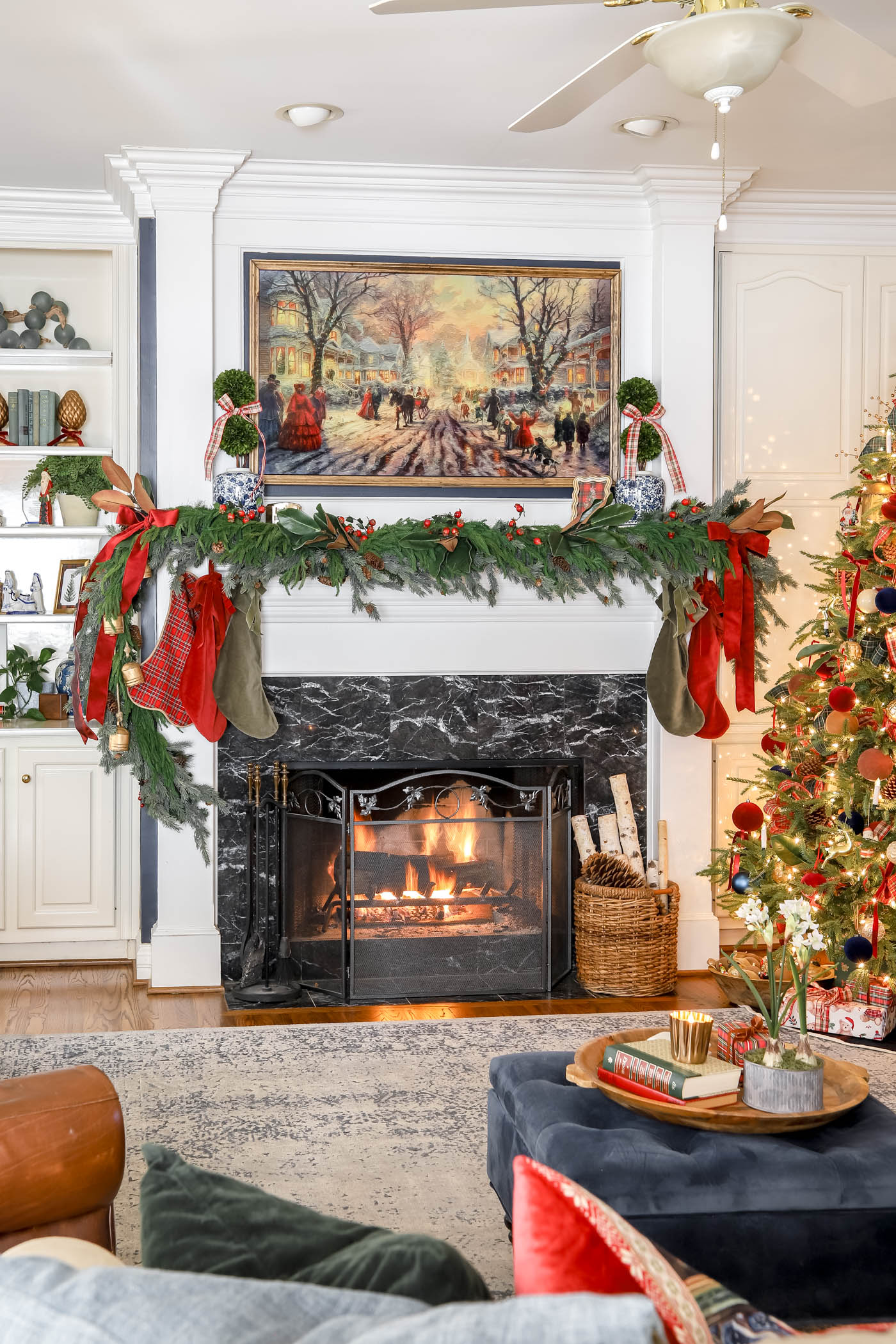 asymmetrical classic mantel for Christmas with garland and pops of red.