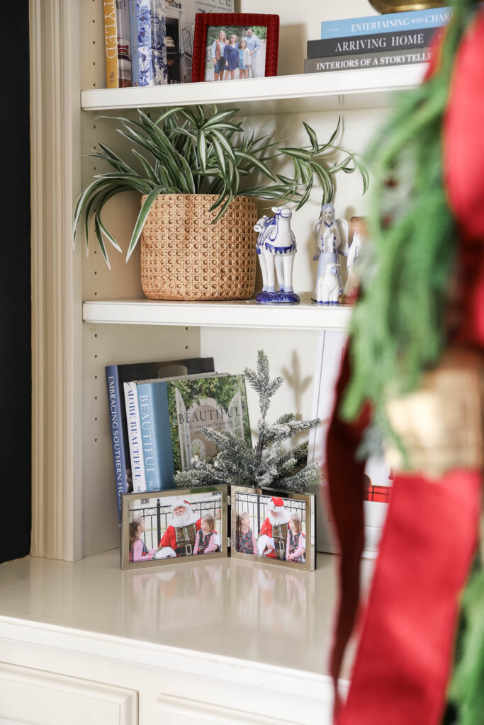 Christmas family photo with Santa in silver frame in a bookshelf decorated for Christmas.