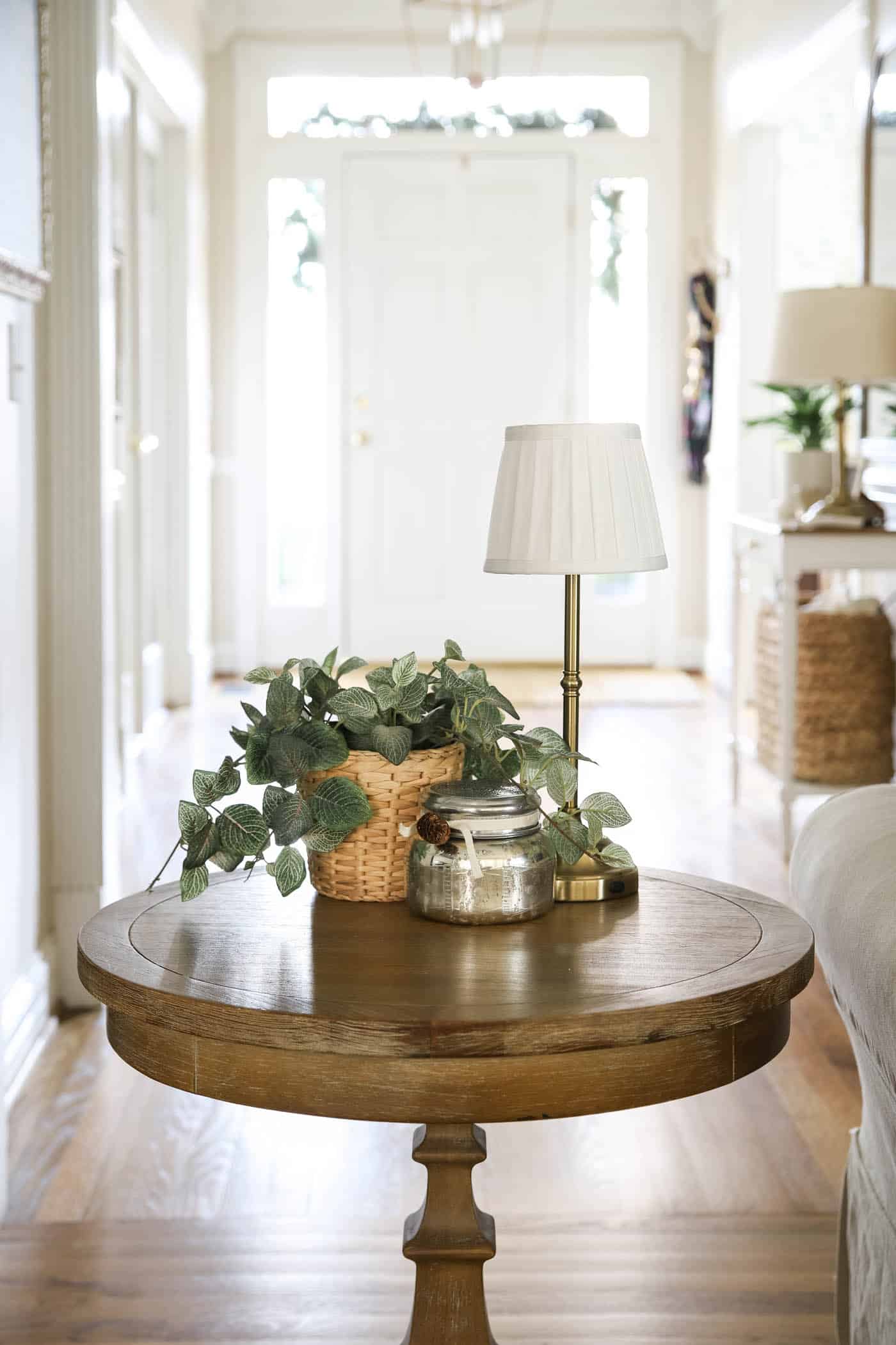 Mini cordless lamp on an end table with greenery and a candle.