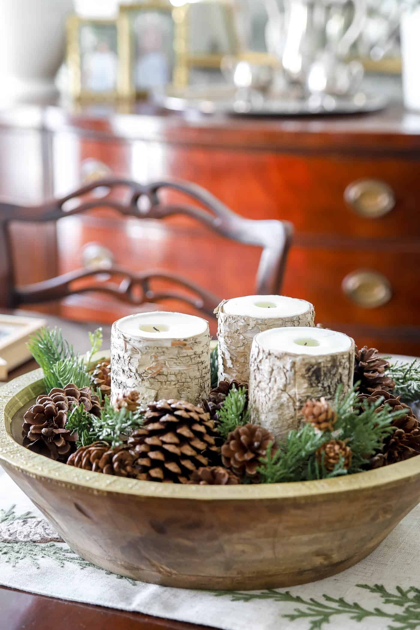 winter pinecones and pops of greenery in a large bowl with candles.