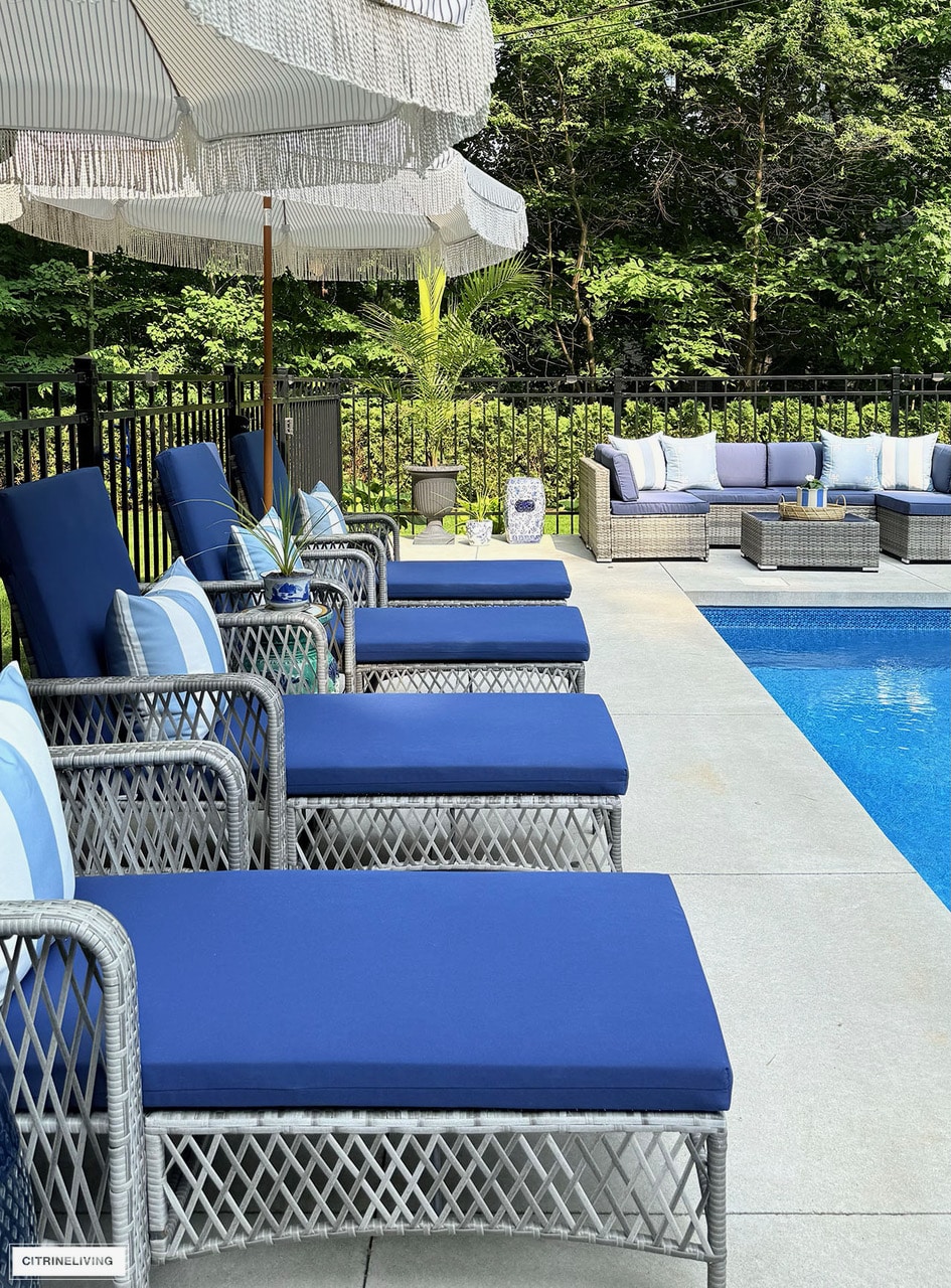 Backyard pool patio ideas with blue lounge chairs, wicker outdoor sectional and navy outdoor decor