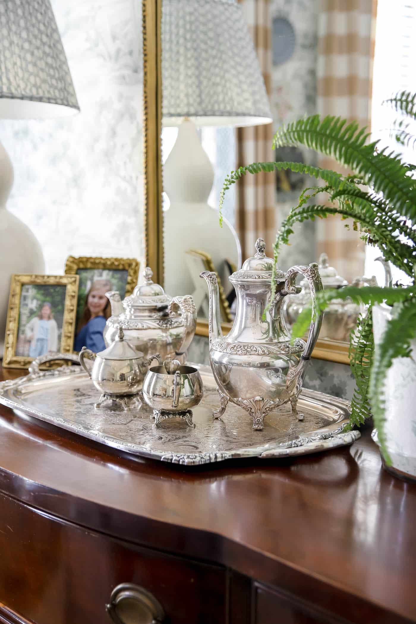 silver tea tray, coffee pot, tea pot and cream and sugar pots on a wood dining buffet. 